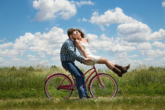 Girl sitting on partners bike kissing him in a paddock