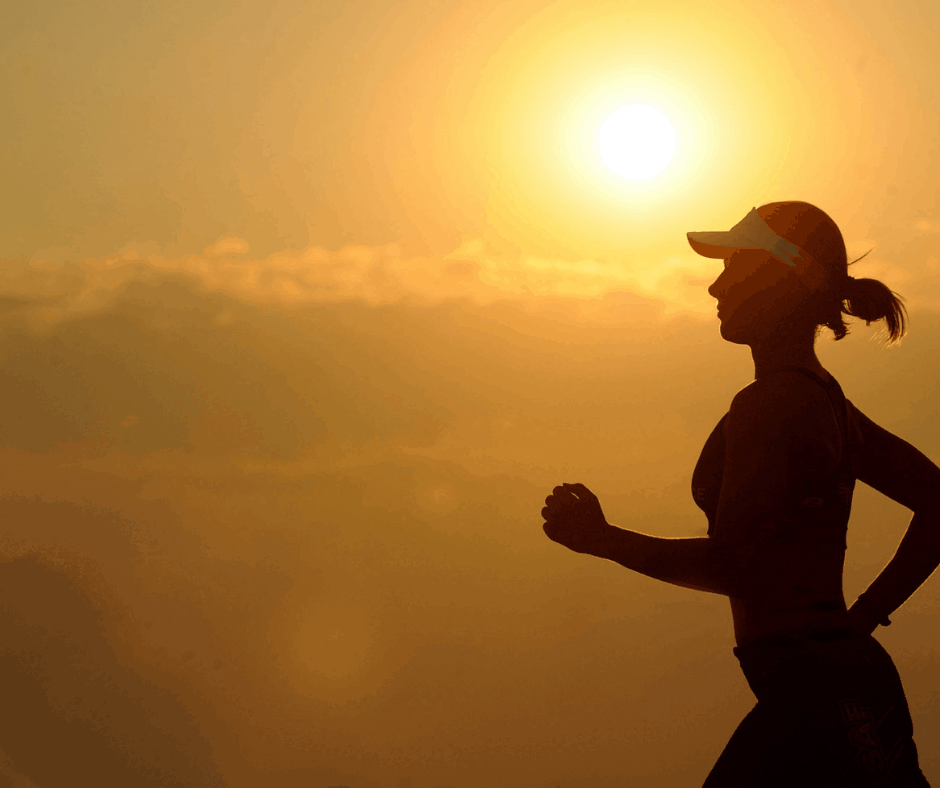 Girl running with visor on with a yellow sunset in the background