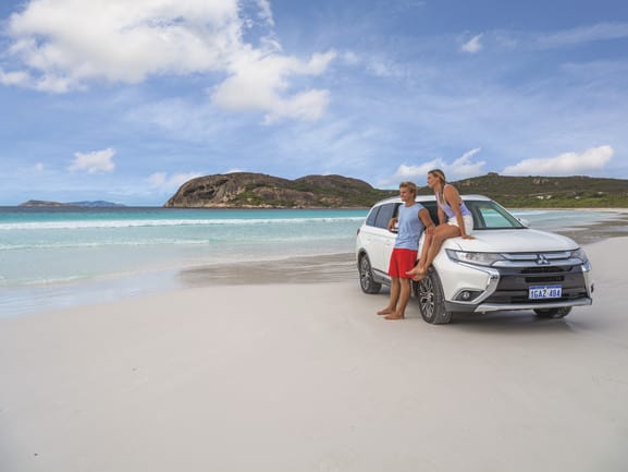 Couple leaning on car at the beach at Lucky Bay, Cape Le Grand National Park