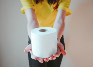 Girl with yellow shirt holding white toilet paper roll
